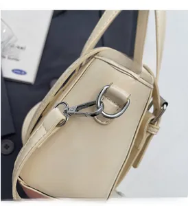 Detailed close-up of premium silver-toned metal hardware on a cream leather bucket bag
