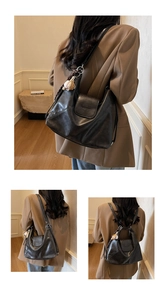 Detail of black soft leather tote bag with woven handle and baseball pendant decoration