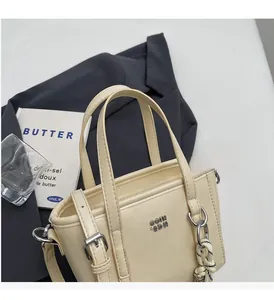 Detailed view of off-white bucket bag with silver buckle and woven rope pendant