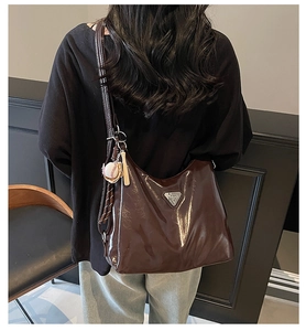 Detail der dunkelbraunen Hobo-Tasche aus glänzendem Wachsleder mit Baseball-Anhänger