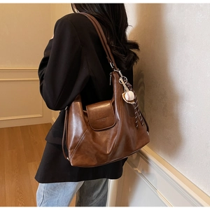 Detailed side view of brown faux leather tote bag with a baseball charm and tassel
