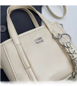 Close-up of cream leather bucket bag showing silver metal logo and woven rope detail