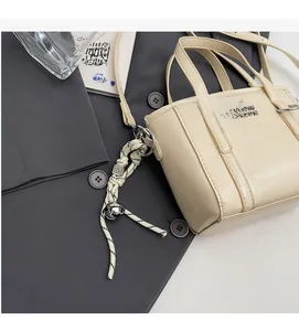 Detailed side view of a cream leather bucket bag with woven knot charm and thin strap