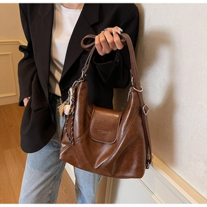 Detail of vintage brown leather tote bag with stylish baseball charm on the side