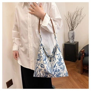 Detailed macro view of the intricate blue floral Toile de Jouy print on the white canvas tote