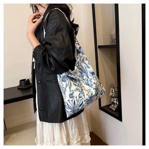 Detail of white canvas tote bag with blue floral embroidery worn on the shoulder