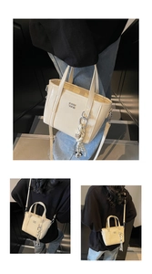Detail view of cream bucket bag with metal letters and braided bell pendant charm