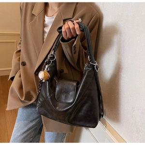 Detail of vintage soft leather tote bag with baseball charm and textured surface