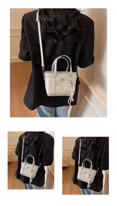 Detail of light grey bucket bag featuring a woven charm and adjustable crossbody strap