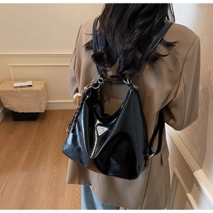 Rückansicht eines Models mit einer schwarzen Lackleder-Tote-Bag mit silbernem Logo