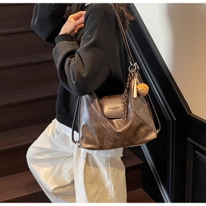 Detail of vintage brown leather tote bag with cross-stitch and tassel charm on stairs