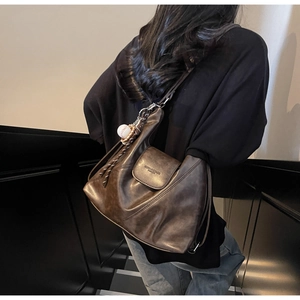 Detail of dark brown vintage leather tote with cross stitching and baseball pendant detail
