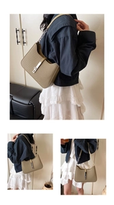 Detail view of woven khaki green underarm bag with silver chain strap and metal buckle