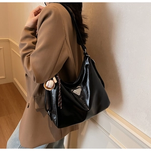 Detailansicht der schwarzen Hobo-Tasche aus Ölwachsleder mit dreieckiger Logoplakette