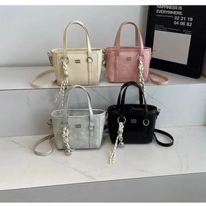 Chic bucket bags in beige, pink, grey, and black with woven charms on marble steps