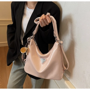 Detail der hellrosa gewachsten Ledertasche mit silbernem Dreieckslogo und Webanhänger