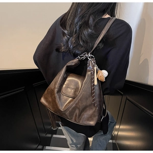 Close-up of retro brown faux leather tote bag featuring a baseball glove charm and logo