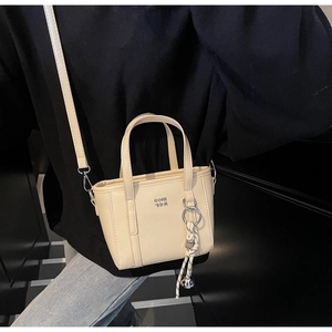 Detail of cream white PU leather bucket bag with metal letters and woven bell charm