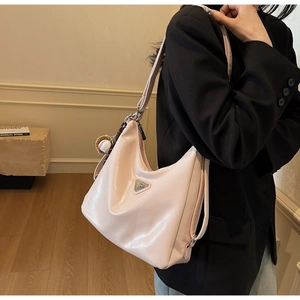 Detail der rosa glänzenden Hobo-Tasche aus Leder mit Baseball-Anhänger und Logo