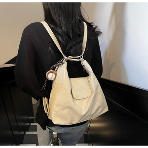 Detail of soft cream PU tote bag with switchable shoulder straps and baseball charm