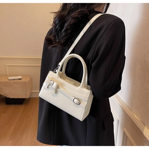 Detail of cream crossbody bag with bow strap shown on a black oversized blazer