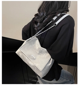 Détail du sac cabas argenté texturé avec bandoulière chaîne porté par un mannequin