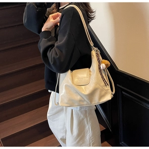 Detail of off-white faux leather tote bag showing diagonal stitching and magnetic flap closure