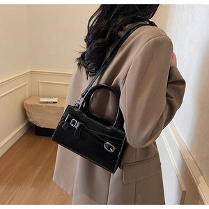 Side view of black glossy leather crossbody bag with bow detail on a stylish model