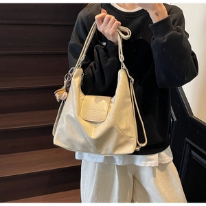 Close-up of cream soft leather tote bag with magnetic flap and athletic charm detail