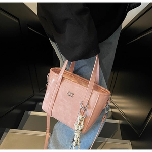 Close-up of pink bucket bag showing PU leather texture and silver brand logo detail