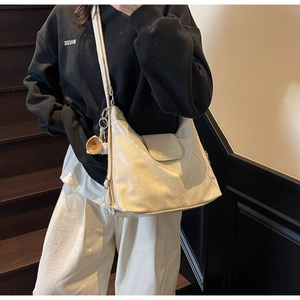 Detail view of cream soft leather tote bag with embossed logo and baseball charm