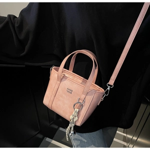 Pink mini leather bucket bag with top handles and a decorative woven rope charm detail
