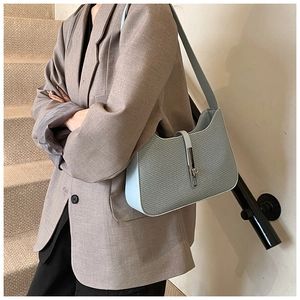 Detail of light blue woven underarm bag featuring a metallic silver clasp and wavy edge