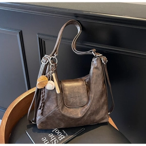 Detail of dark brown vintage Hobo bag with magnetic flap and baseball themed keychain
