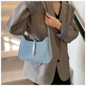 Close-up of light blue woven texture shoulder bag with elegant silver metal buckle