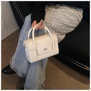 Detail of a white glossy square handbag featuring metal logo and dual round handles