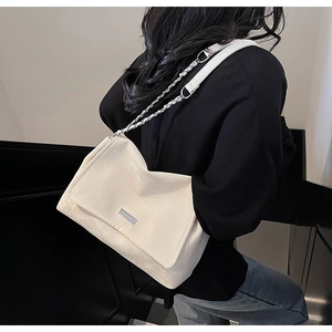 Détail du sac cabas crème avec logo en métal et bandoulière en cuir sur le mannequin