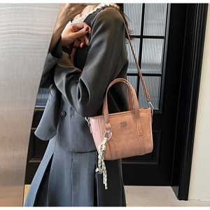 Detail of a pink leather bucket bag with silver logo and decorative bell charm