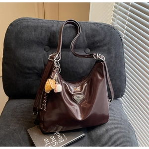 Detailansicht der braunen Ledertasche mit glänzendem Finish und Metall-Logo-Plakette