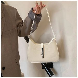 Close-up of cream woven underarm bag featuring silver chain and adjustable strap detail