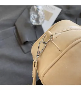 Macro shot of high-shine silver metal buckles and zippers on a beige leather handbag