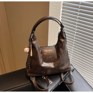 Detail of dark brown vintage soft leather tote bag with unique baseball keychain accessory