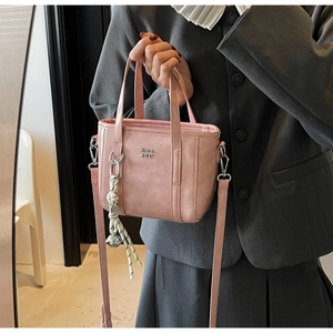Detailed close-up of pink bucket bag with textured leather and contrast woven pendant