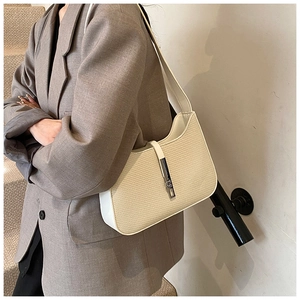 Detail view of cream woven shoulder bag on model wearing a modern brown blazer