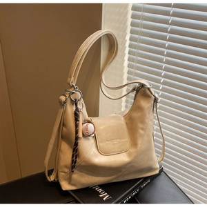 Detailed macro view of beige PU leather tote bag with branded pocket and baseball charm