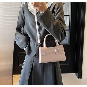 Detailed side view of a pink minimalist square handbag with metal buckle and bow accent