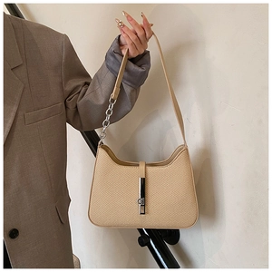 Detail shot of beige woven underarm bag featuring silver chain and metal clasp