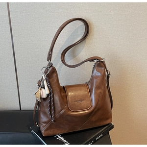 Detail view of brown soft PU leather tote bag with embossed logo and baseball charm