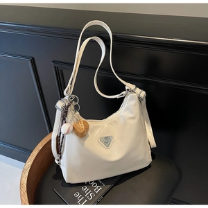 Detail der cremeweißen Hobo-Tasche aus Kunstleder mit Metall-Logo und Anhänger