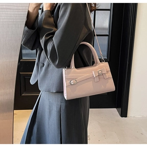 Pink square handbag with bow detail worn by a model in a charcoal blazer and skirt